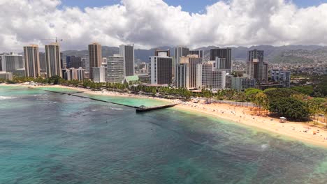 sunny day at waikiki beach with pier, reef, and honolulu skyline