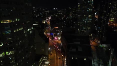 Toma-Nocturna-De-Un-Dron-Volando-Por-El-Centro-De-Toronto-Con-Muchas-Luces-De-La-Calle-Y-Autos-A-La-Vista