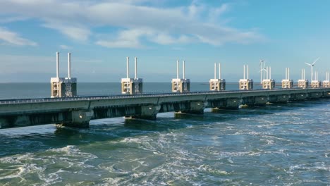 Toma-Aérea-De-Agua-Que-Fluye-A-Través-De-La-Barrera-De-Marejada-Ciclónica-Del-Este-De-Scheldt-En-Zelanda,-Los-Países-Bajos,-En-Un-Hermoso-Día-Soleado