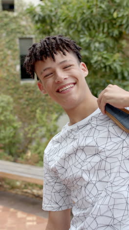 vertical video: in highschool, biracial teenage boy is smiling brightly