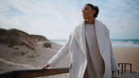 Relaxed-model-lean-wooden-pier-at-ocean-shore.-Serene-african-woman-enjoy-breeze