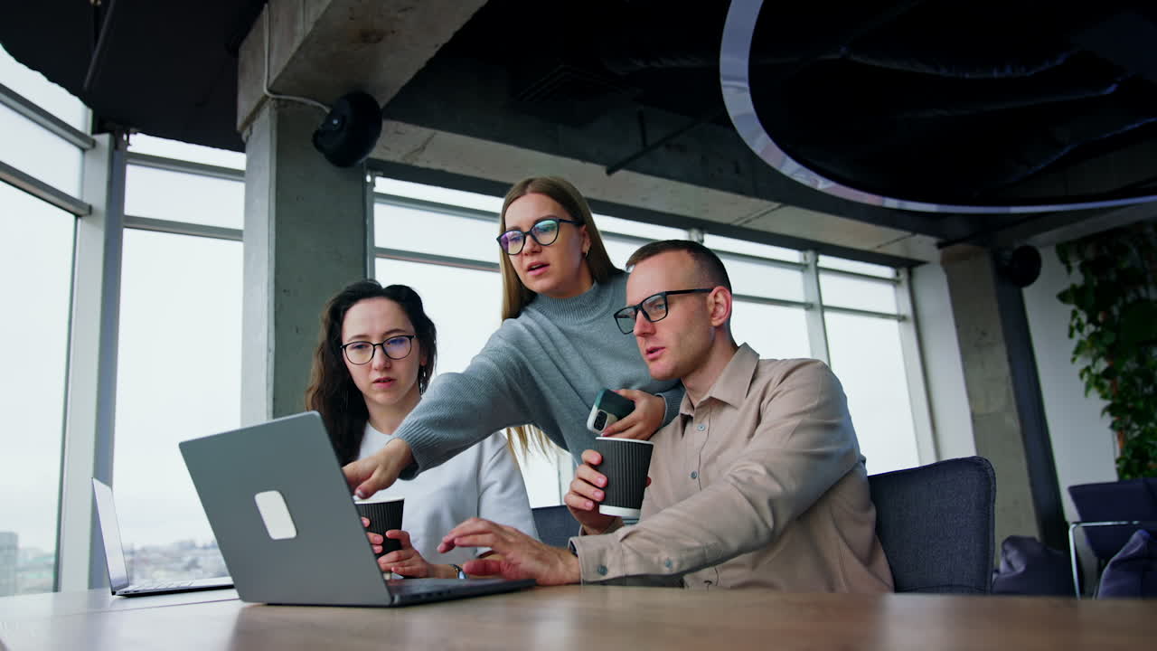 Producing ideas in the teamwork. Three office employees look at laptop and brainstorm, searching options and talk. Low angle view.