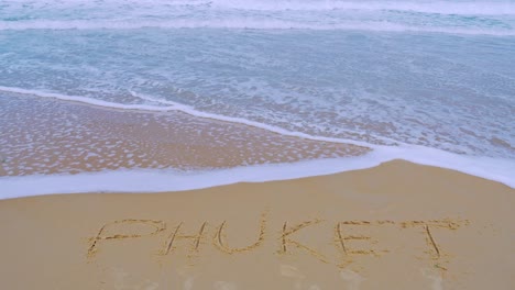 text phuket on the sea beach and splashing waves on the sand with the slow motion wave in nature concept