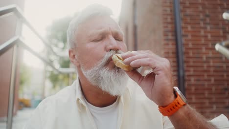 senior man eating a sandwich outdoors