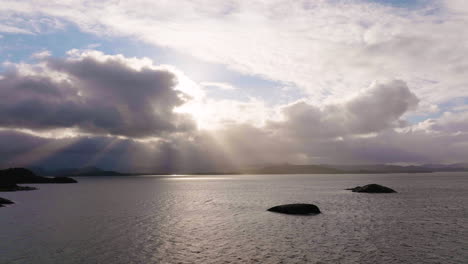 crepuscular rays  shine through clouds over coastline; aerial