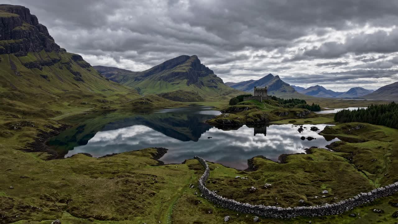 Aerial view of a serene landscape with a castle by a lake, under a cloudy sky