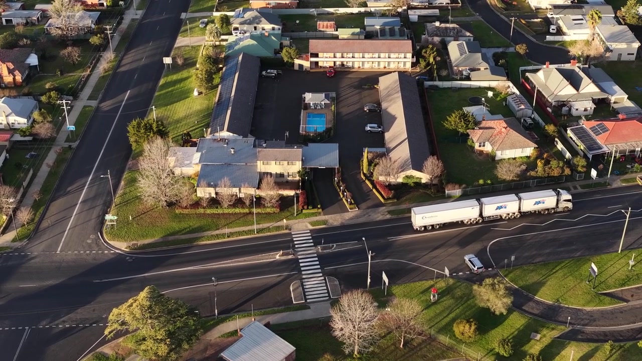 Ripresa aerea con drone di un camion merci che passa accanto a case residenziali a Coonabarabran, Australia.