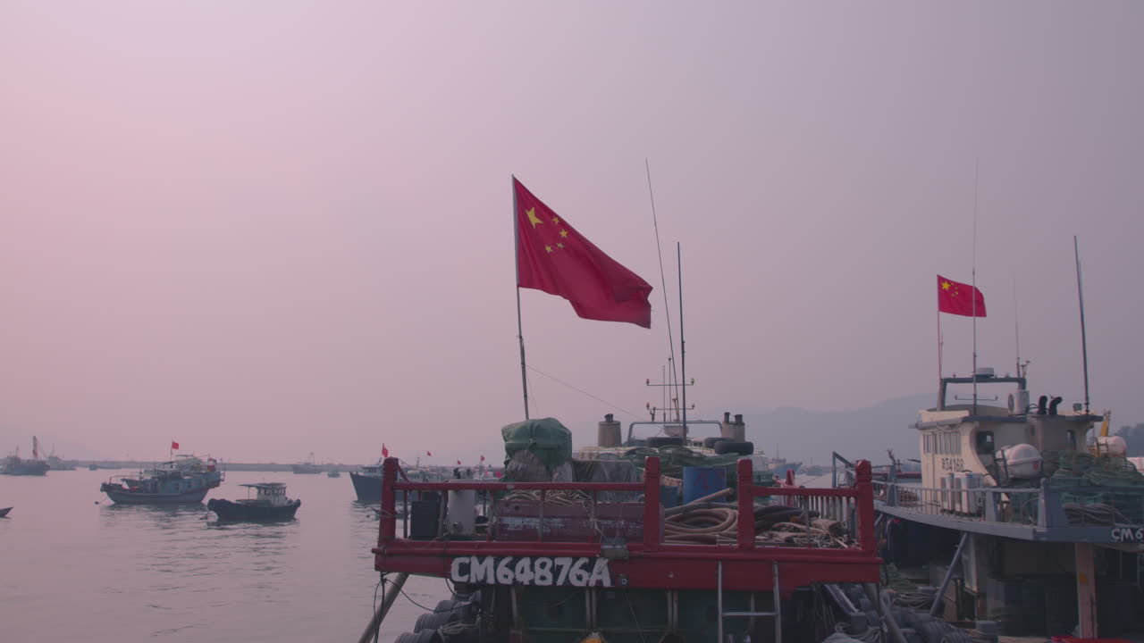 Chinese flag in the wind on a small boat during sunset in an little harbor