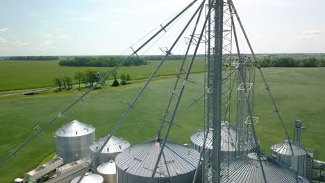 aerial view rising over industrial metallic grain silo storage processing on arcadia agricultural farmland, indiana