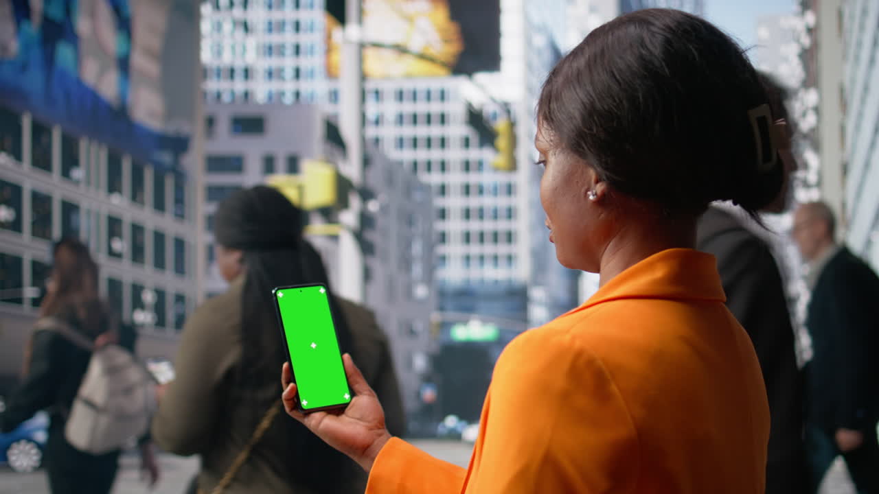 Vertical isolated screen on phone held by black woman near group of pedestrians