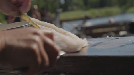 Mann-Schneidet-Fischfilets-Mit-Messer-Auf-Holzschneidebrett-Im-Freien-In-Der-Natur,-Zeitlupe