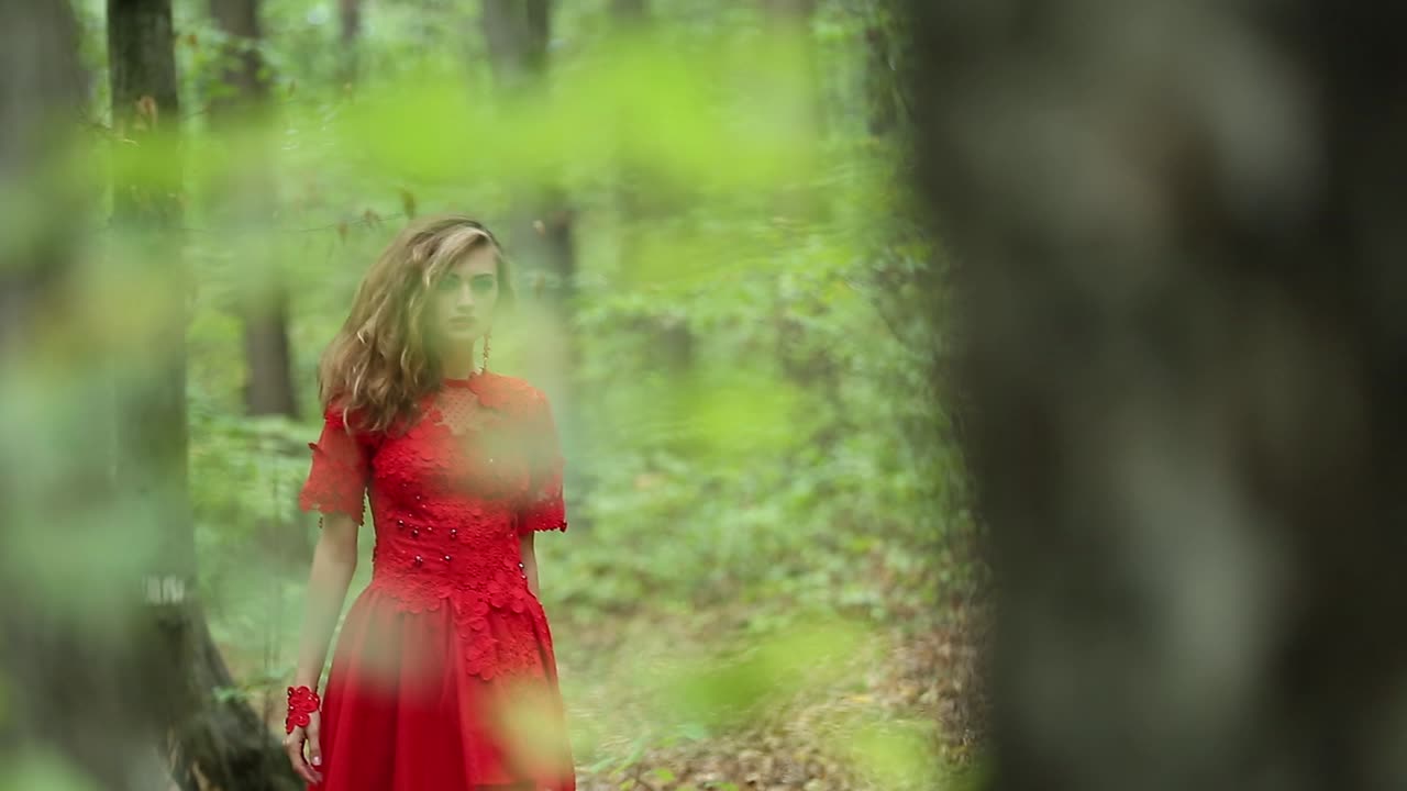 Beautiful Woman Walking Through Green Forest. Beautiful woman in red long dress walking through green forest