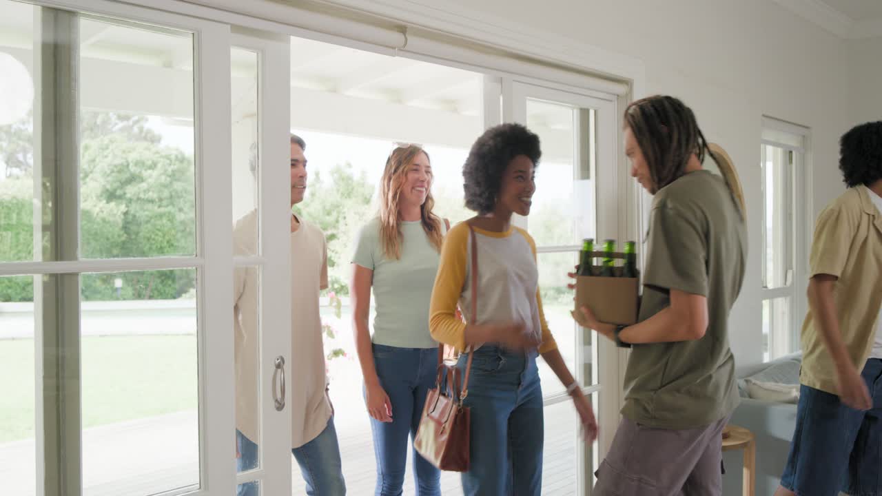 Friends arriving host with dreads opening doors, handing drinks and hugging for party, copy space