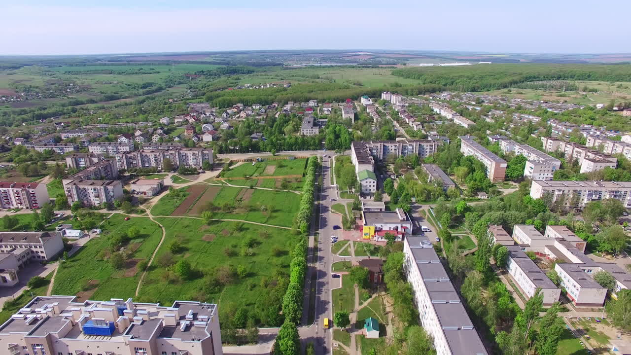 Provincial city panorama shot on sunny day in summer. Residential neighborhoods and green zones from aerial perspective.