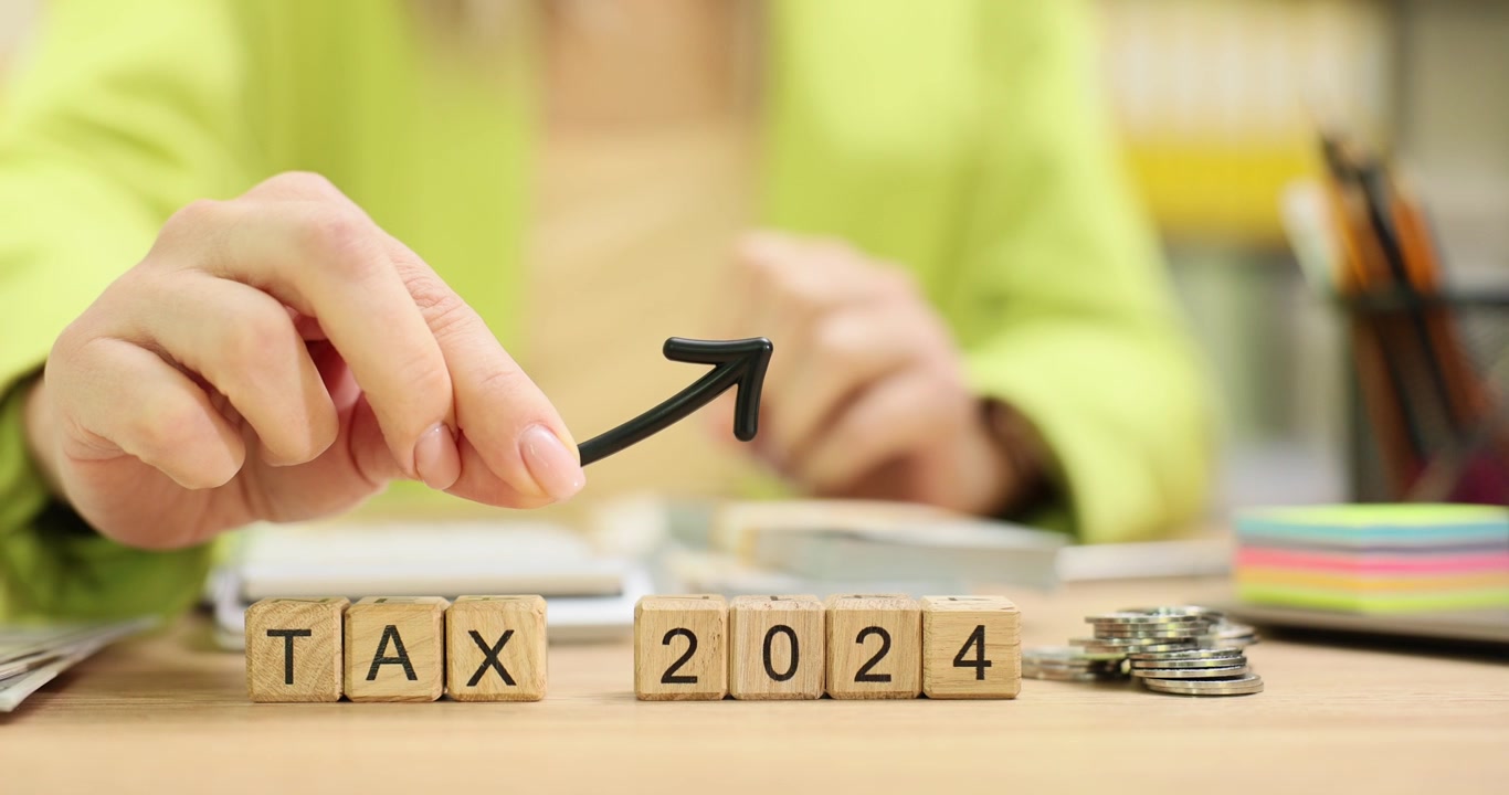 Woman holds arrow above phrase tax 2024 from cubes in office