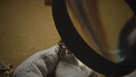 jeweller analyses ring gemstones with magnifying glass loupe close-up