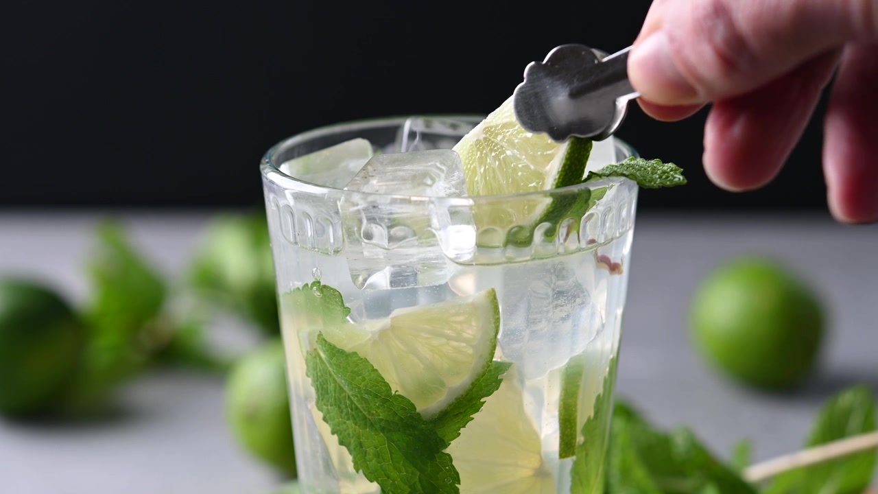 Limelohkon asettaminen mojito-cocktail-lasiin tuoreen mintun kera