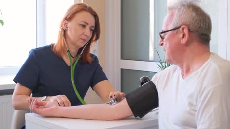 female cardiologist measuring blood pressure of an elderly patient at doctor’s office. an elderly man is examined by a doctor.