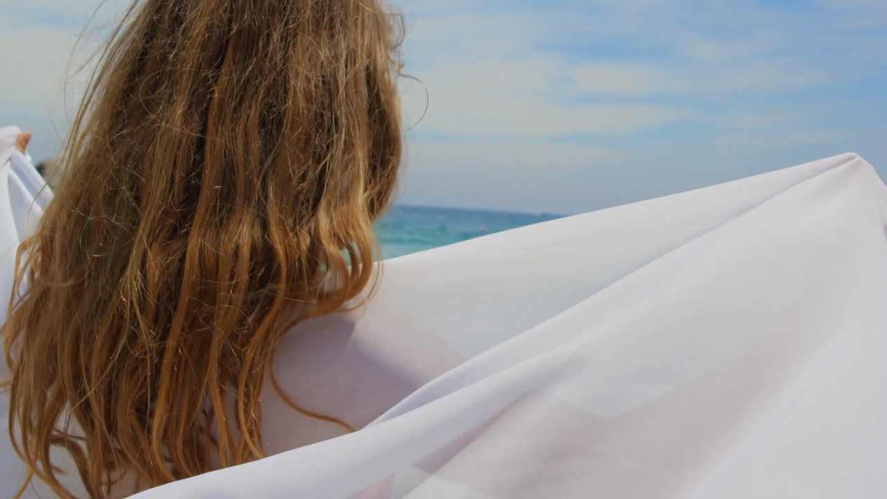 해변에서 사롱으로 싸인 백인 여성의 뒷면 4k