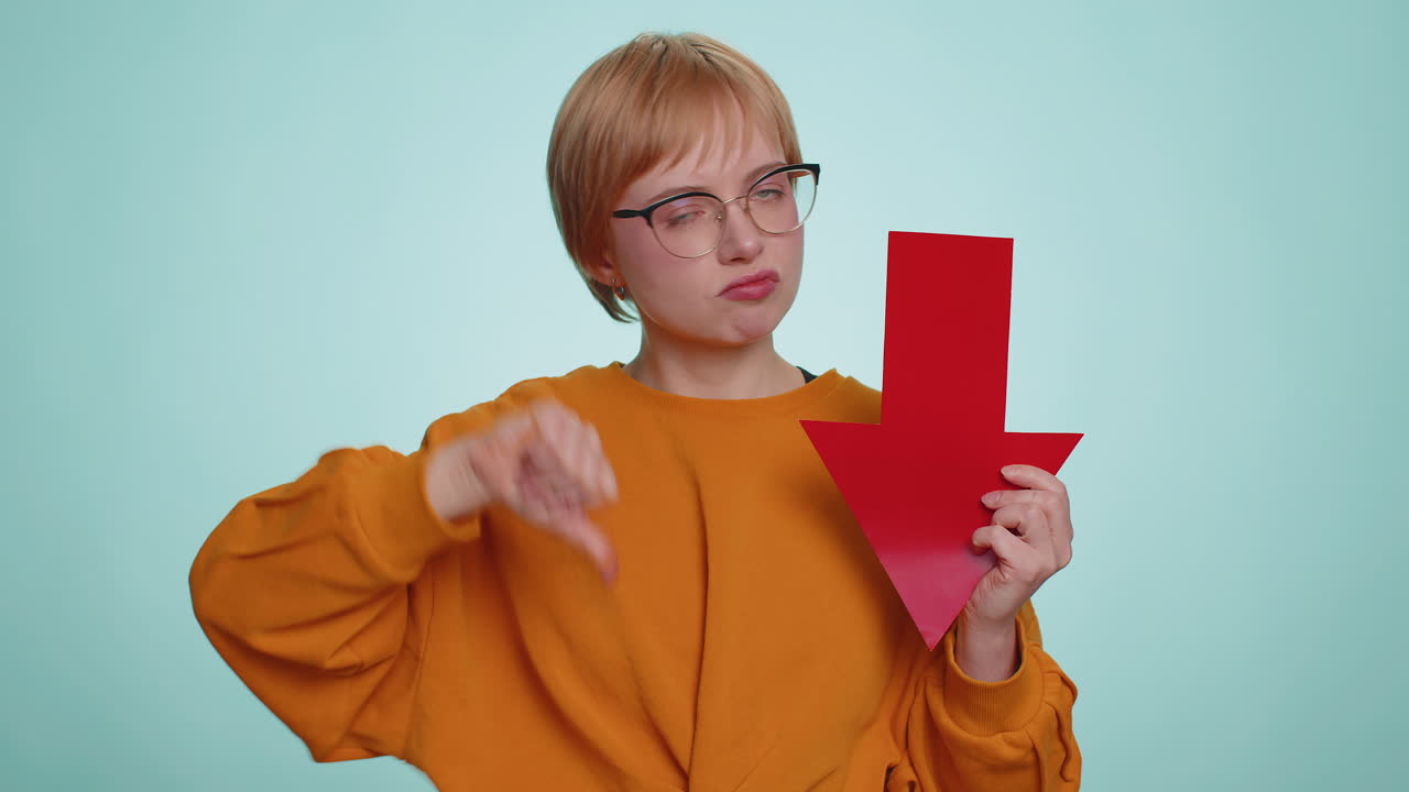 Upset sad woman showing red arrow pointing down concept of downgrade bankruptcy money fail fall