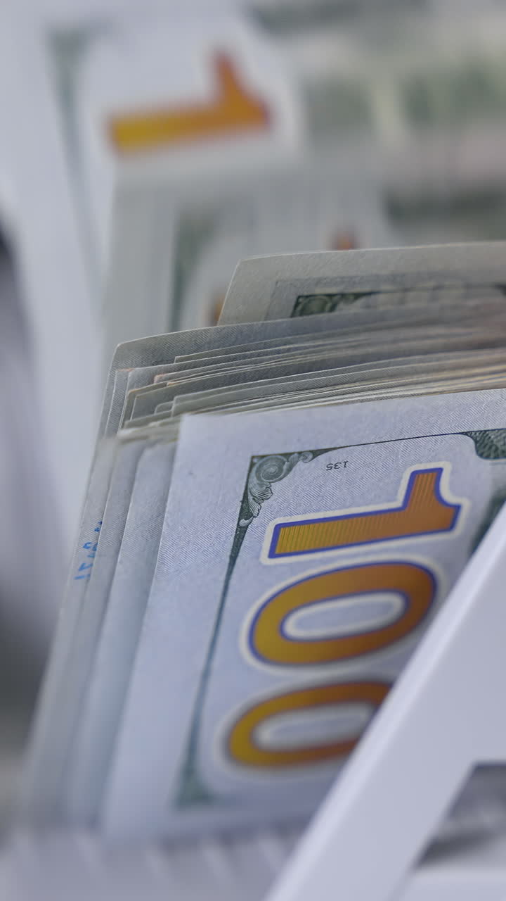 Paper cash money calculation. Electronic money counter machine is counting paper banknotes. Detailed view currency of hundred bills on counter machine. Vertical video