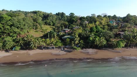 Costa-Rica-beach-drone-view-showing-sea,-shore-and-palm-tree-forest-in-Corcovado-National-Park-on-Osa-Peninsula-on-a-sunny-day-in-the-pacific-ocean