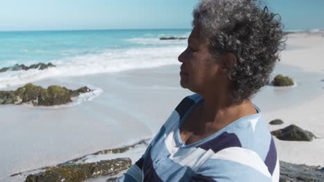 Senior-woman-sitting-on-a-rock-at-the-beach