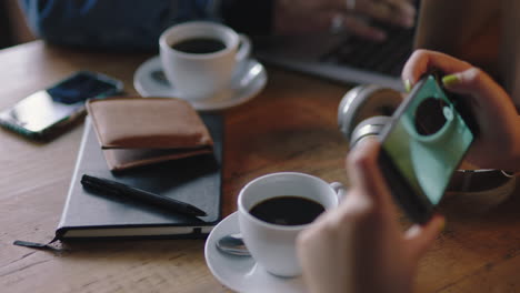 Cerrar-Las-Manos-Grupo-De-Amigos-Usando-Un-Teléfono-Inteligente-En-Una-Cafetería-Tomando-Una-Foto-De-Un-Café-Compartiendo-Fotografías-En-Las-Redes-Sociales-Disfrutando-Socializando-Juntos