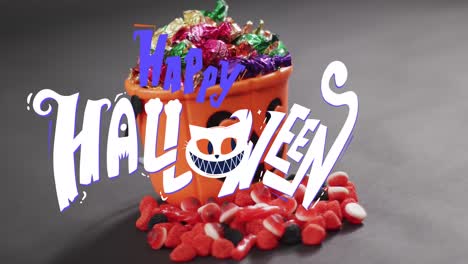 Animation-of-happy-halloween-text-over-orange-pumpkin-bucket-with-sweets