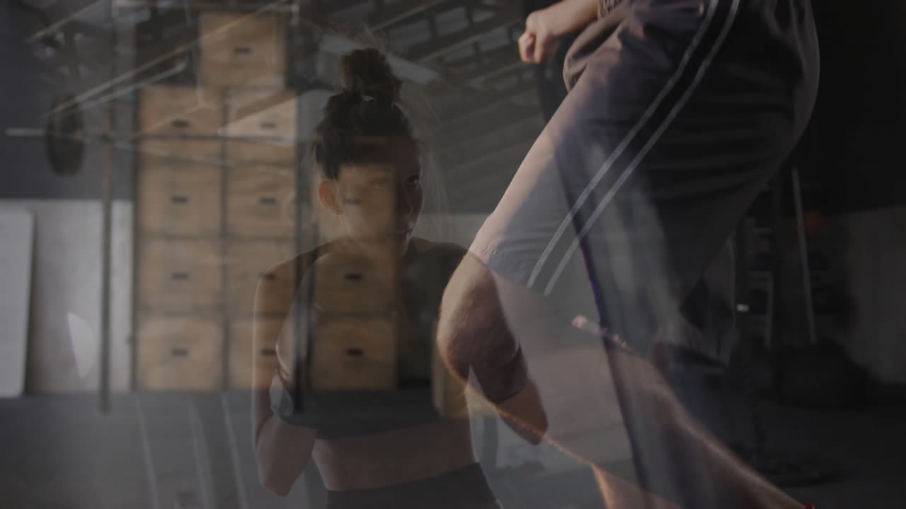 Donna in palestra che pratica mosse di boxe, con casse di legno sullo sfondo.