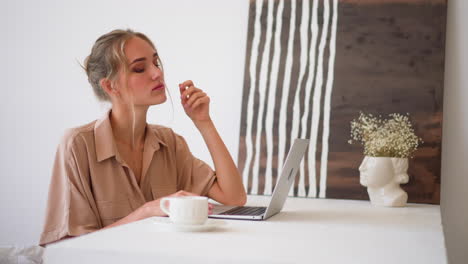 blonde woman checks information in laptop at home office