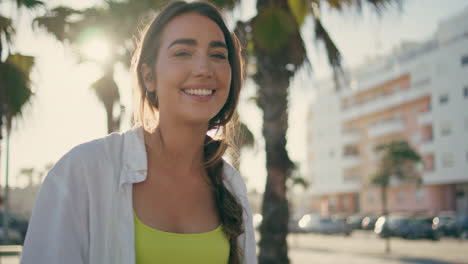 una chica sonriente caminando por la naturaleza tropical en primer plano. una mujer feliz y relajada mirando a la cámara.