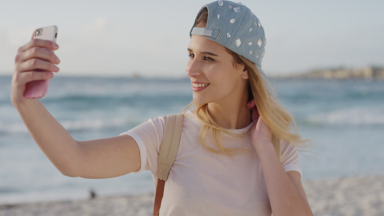retrato de una linda mujer rubia tomando una foto selfie en la playa usando tecnología de cámara de teléfono inteligente disfrutando de compartir la experiencia de vacaciones en línea comunicación móvil