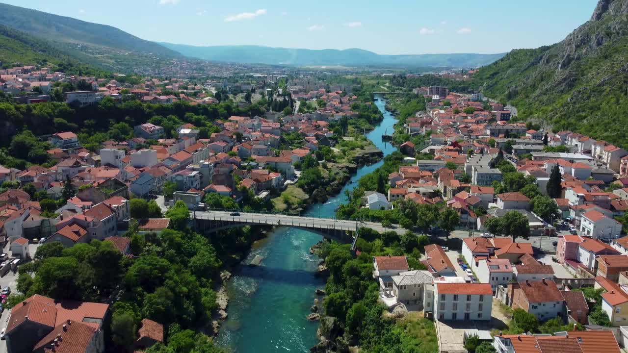 Elevated aerial view of Mostar’s ancient stone buildings, narrow streets, and the bustling area surrounding the UNESCO World Heritage-listed Old Bridge