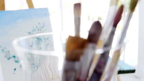 paintbrushes with painting on easel