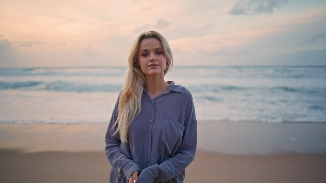 Relaxed woman stepping beach in summer sunset. Smiling blonde on peaceful shore