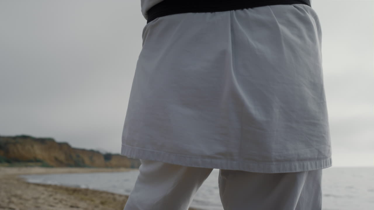 카라테 선수가 해변에서 무술 훈련을 하고 남자가 태권도를 연습하고 있습니다.