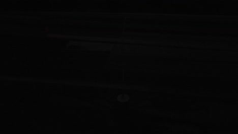a high-mast light flickers on a highway interstate while trucks and cars pass underneath
