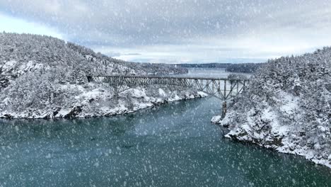 wide aerial view of deception pass in washington state with snow actively falling