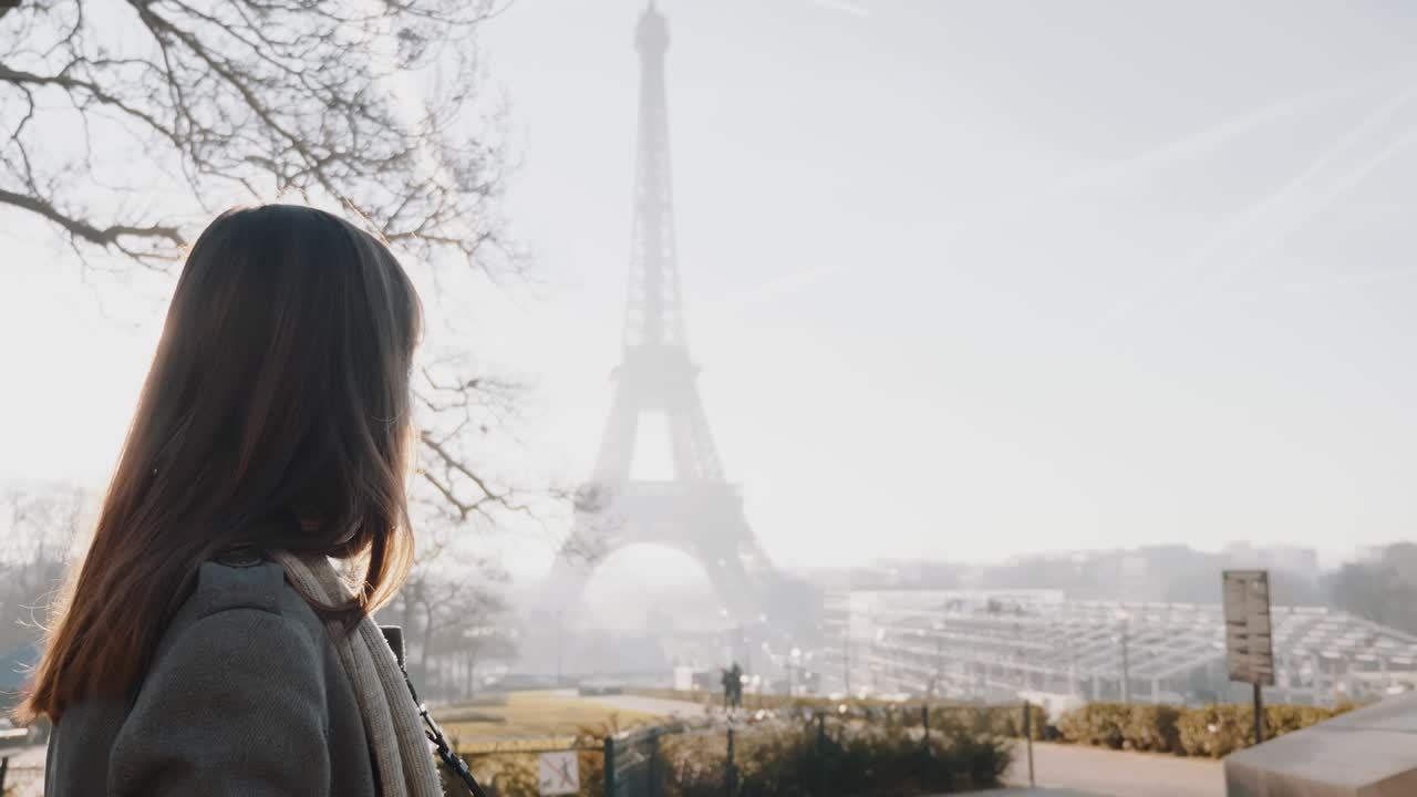 Side view happy Caucasian tourist woman walking along sunrise Paris, famous Eiffel Tower seen in background slow motion.