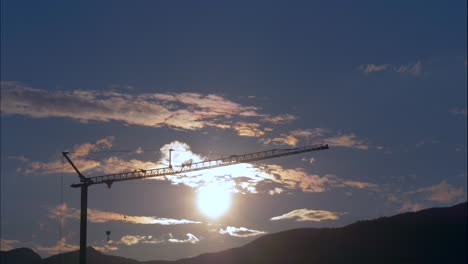 toma de lapso de tiempo de nubes voladoras contra el cielo azul y silueta de grúa al atardecer