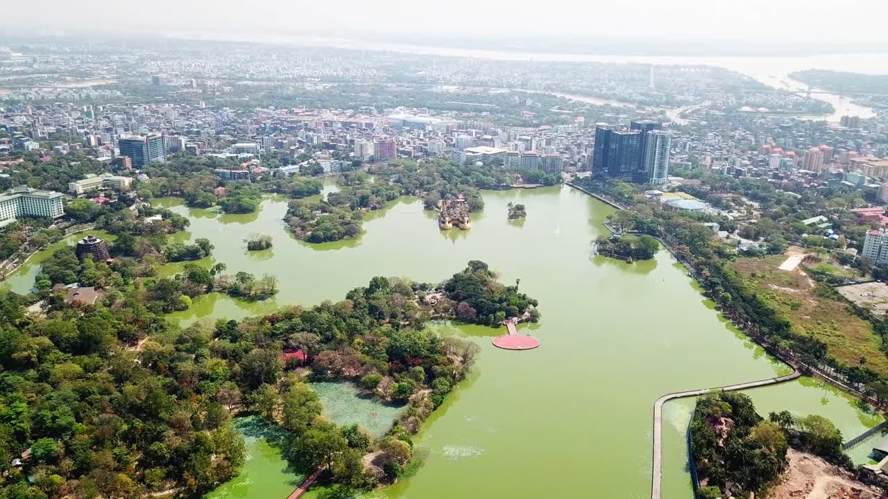una impresionante perspectiva aérea del lago kandawgyi en rangún, myanmar, que muestra sus exuberantes alrededores verdes, pequeñas islas y el vibrante paisaje urbano en el fondo