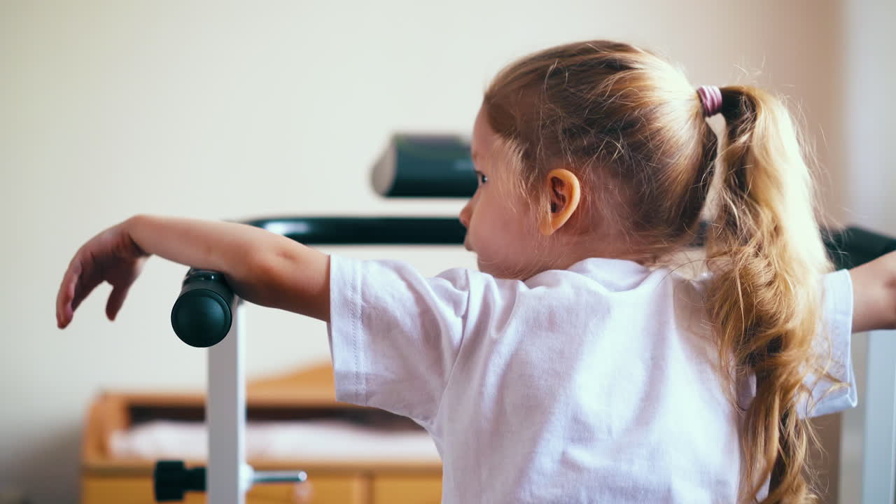 곱슬머리 소녀는 집에서 기계 손잡이를 실행에 의존
