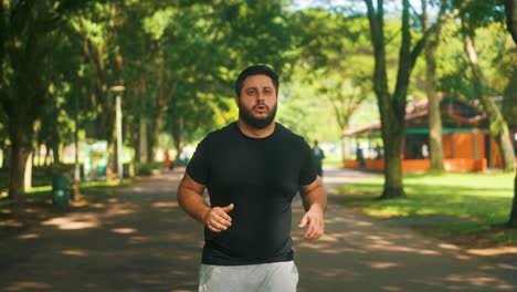 Focused-overweith-guy-jogging-outdoors-at-a-park