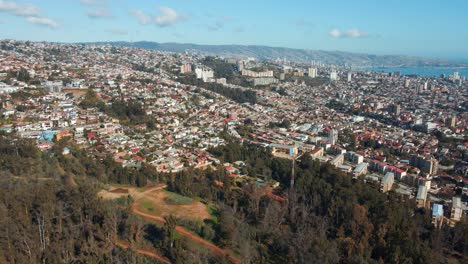 Panorámica-Aérea-A-La-Derecha-De-Los-Edificios-De-La-Ciudad-De-Viña-Del-Mar-Vista-Panorámica-Desde-La-Colina,-Las-Montañas-Y-El-Mar-Al-Fondo,-Chile