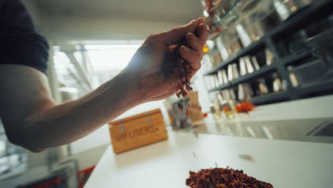 Close-up-shot-of-a-man's-hand-picking-up-bright-aromatic-dried-spice-herbs-from-a-table