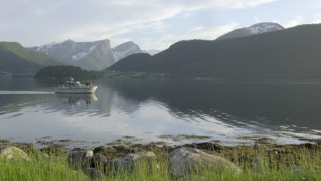 a boat passing by in idyllic surroundings at a lake in norway