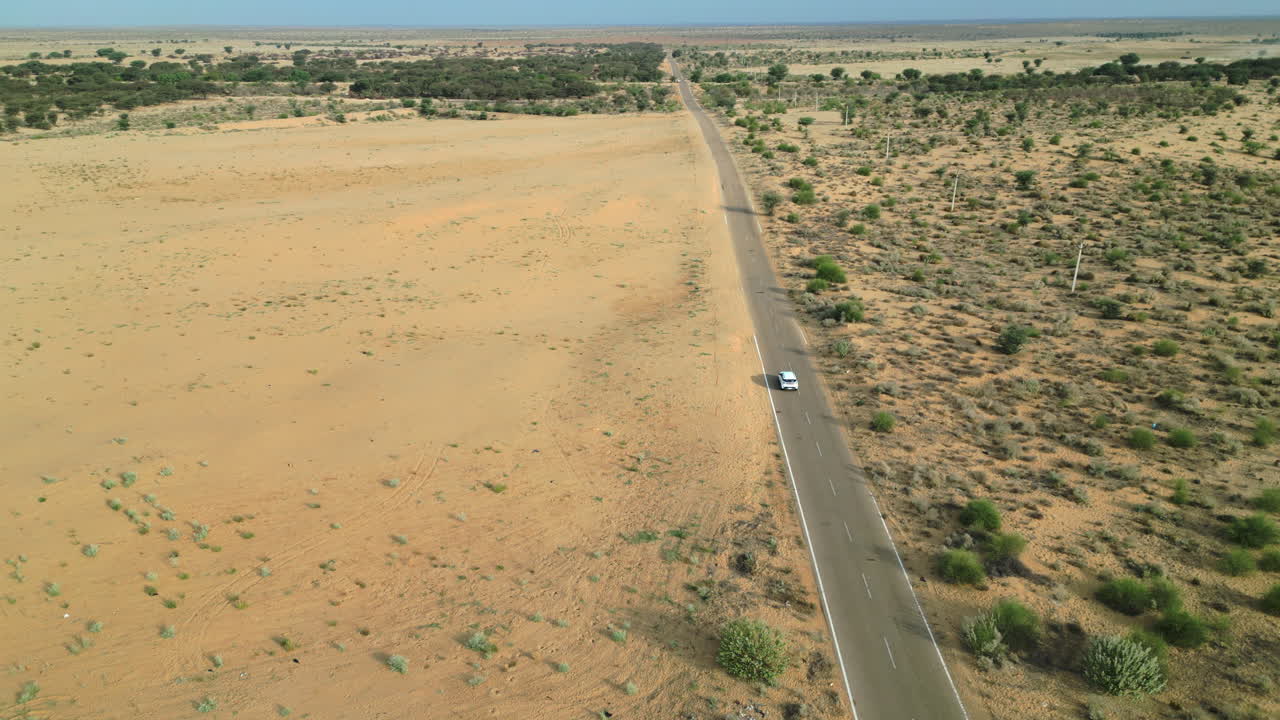 라자스탄의 광활한 사막 풍경을 가로질러 이동하는 자동차의 드론, 명확한 파란 하늘 아래 황금 모래가 끝없이 어 있습니다.
