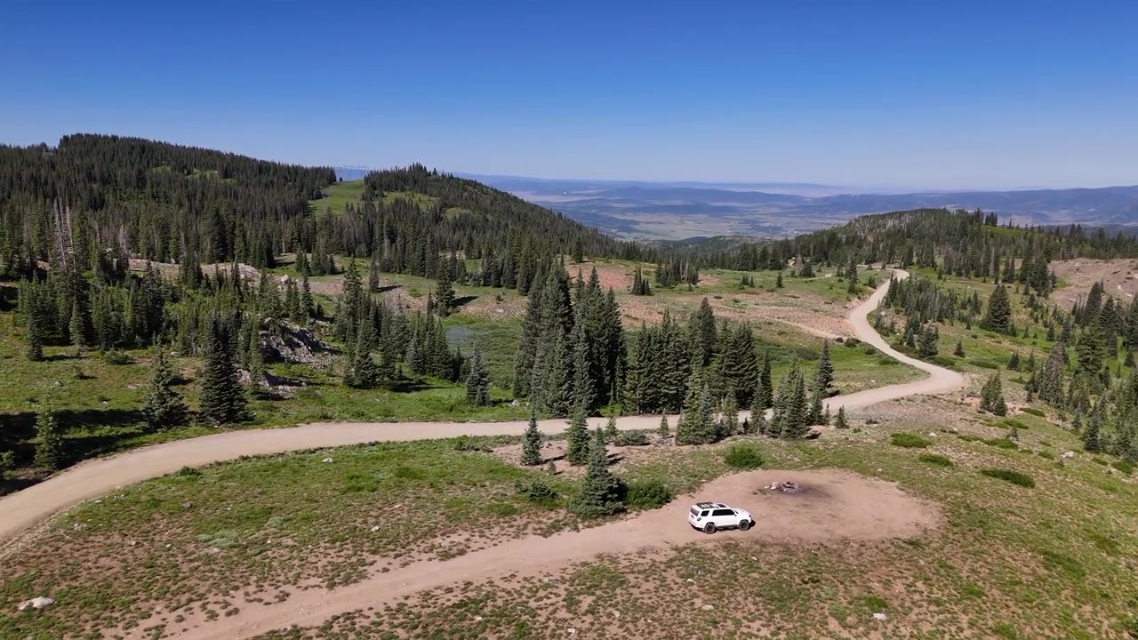 Drönarbild av vit SUV på bergsväg i orört landskap i Park Range, Klippiga bergen, Colorado, USA.