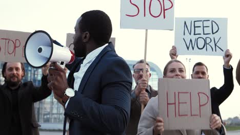 african american man talking on loudspeaker with arms up in a protest with multiethnic business colleagues in the street